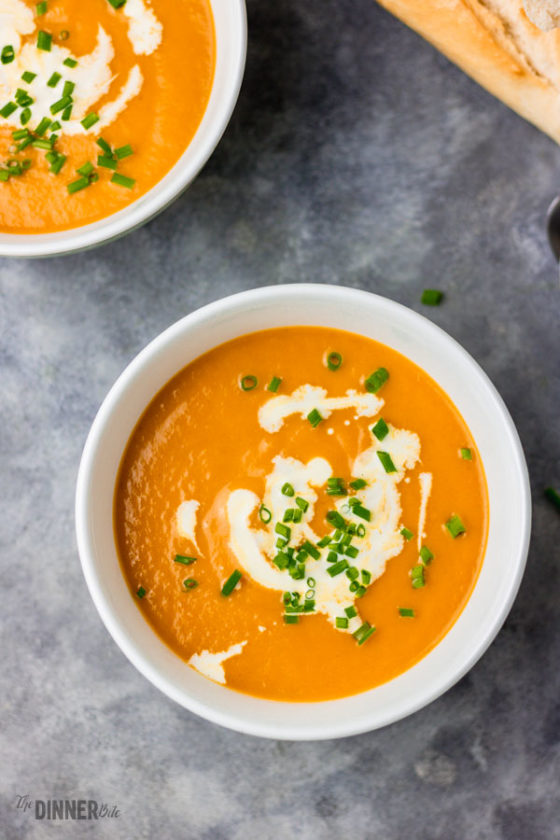 pressure cooker carrot soup served in bowls. garnished with chopped chives and cream