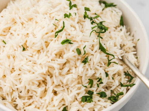 a bowl of coconut rice garnished with chopped parsley.