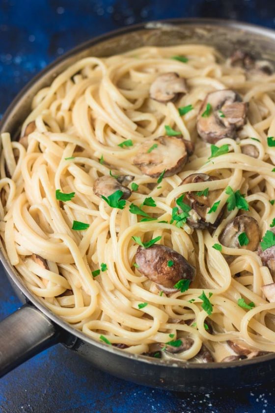 creamy mushroom pasta in a skillet garnished with parsley. 