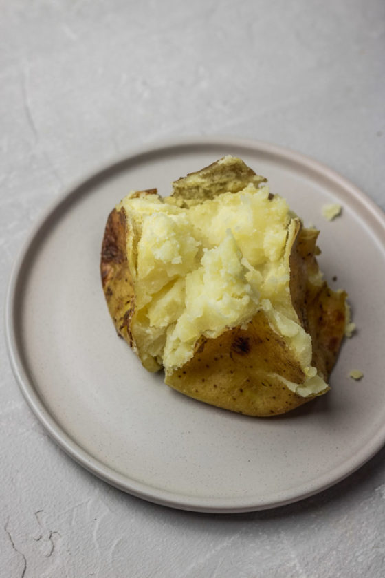 Instant pot baked potatoes in a flat plate.