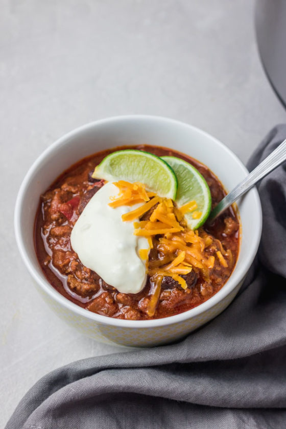 instant pot chilli garnised with sour cream, cheese and lime wedge.