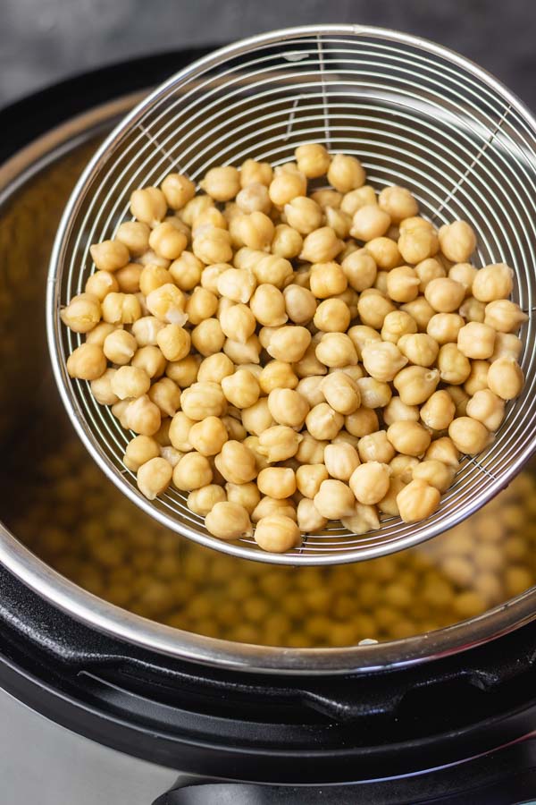 cooked instant pot chickpeas in a colander held over an instant pot.