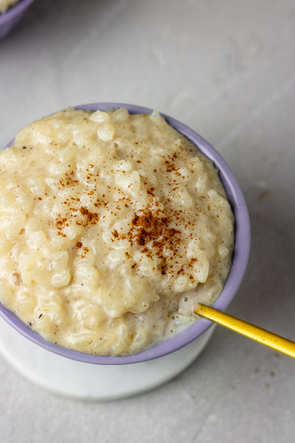 a small dessert bowl of rice pudding lightly garnished with cinnamon powder.