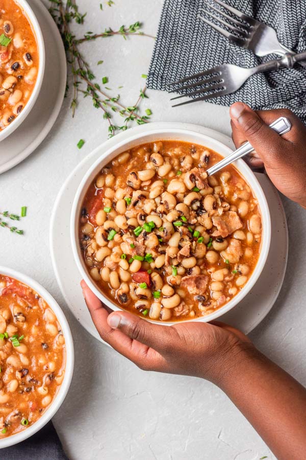 a hand holding a bowl of black eyed peas