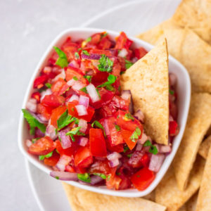 a bowl of pico de gallo salsa served with homemade baked tortilla chips.