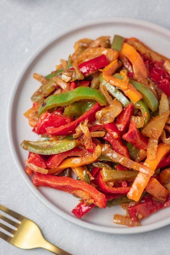 a plate of sauteed peppers made with red, green and orange bell peppers.