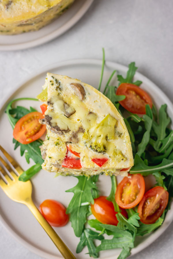 Instant pot frittata wedge served with rocket salad and plum tomatoes.