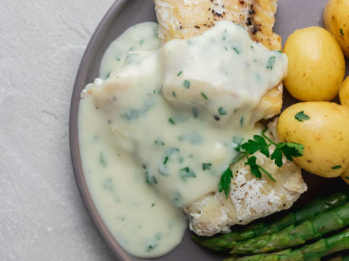 a grey plate with instant pot cod fish, parsley sauce, baby potatoes and asparagus.