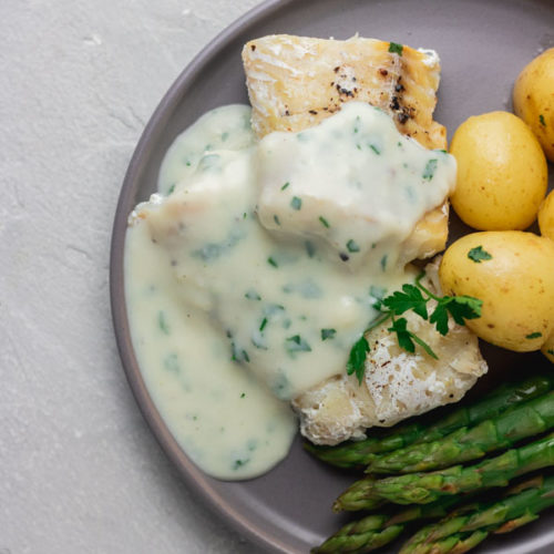 a grey plate with instant pot cod fish, parsley sauce, baby potatoes and asparagus.