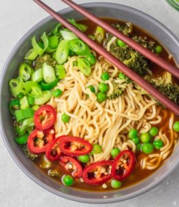 a bowl of instant pot ramen noodles topped with chopped green onions and jalapeno.