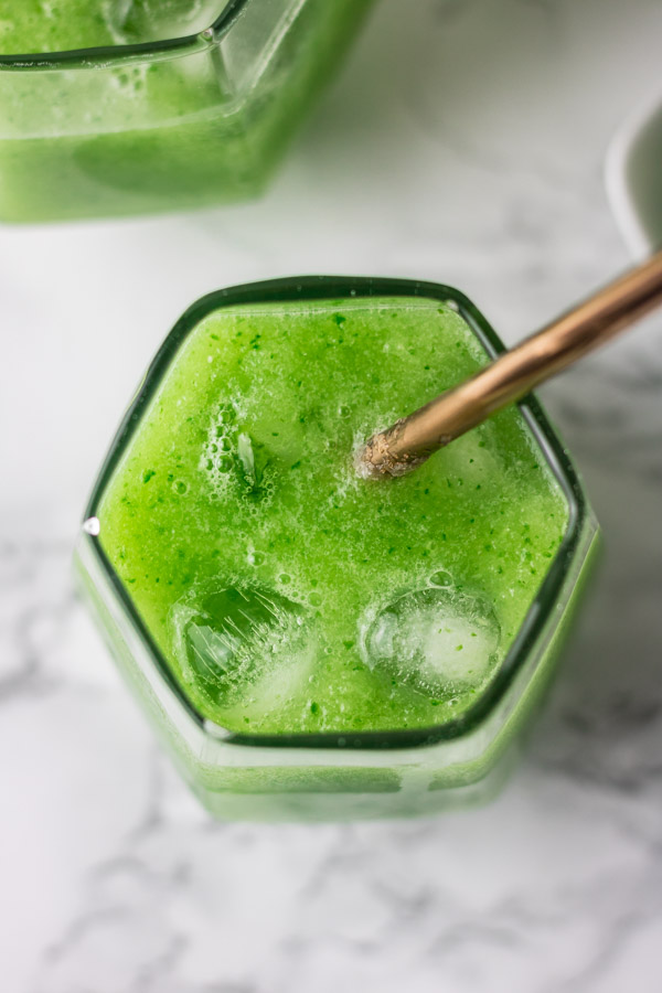 A GLASS OF ICED CUCUMBER JUICE AND A STRAW.