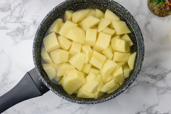 cubed potatoes covered with water in a saucepan.