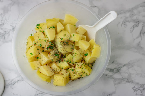parboiled cubed spuds in a bowl with herbs.