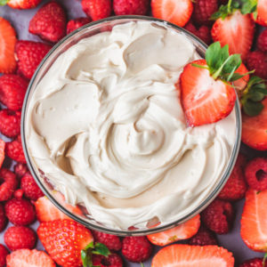 a bowl of homemade cream cheese fruit dip served with strawberries and raspberries.