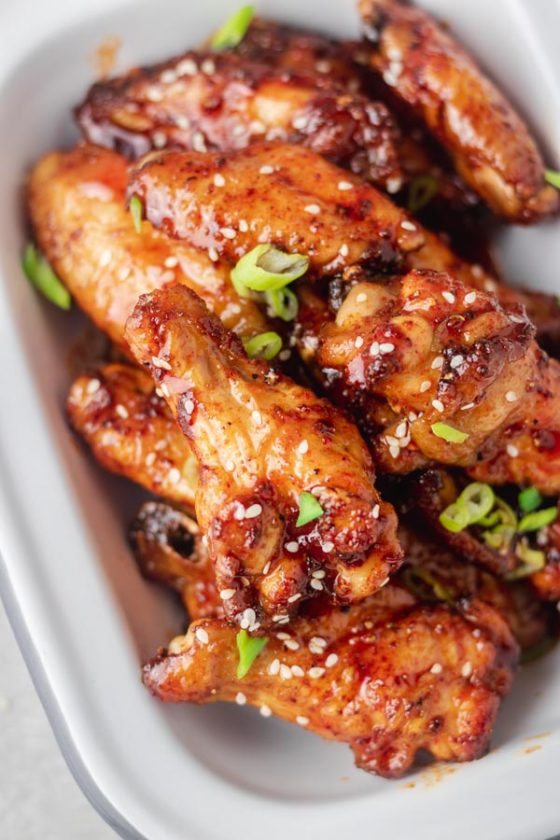 sriracha honey wings garnished with green onions and sesame seeds.