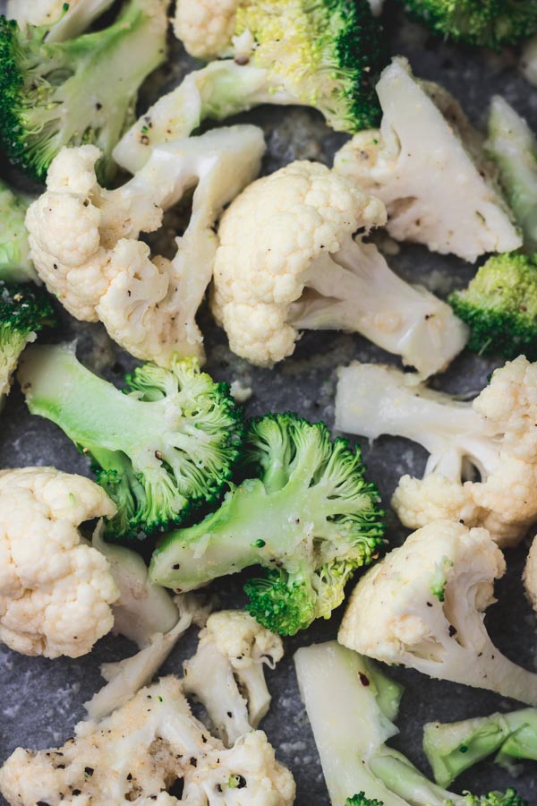 cauliflower and broccoli florets on a oiled baking tray about to be roasted in the oven.