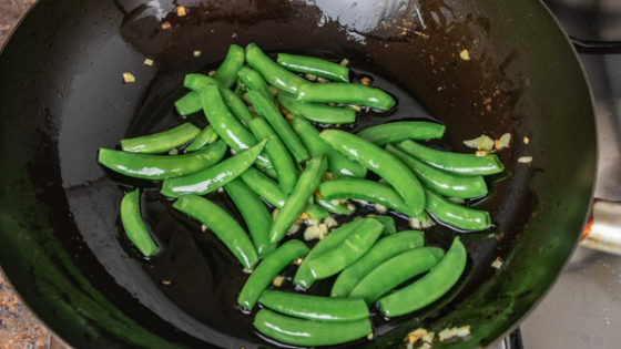 sauteing snap peas in wok.