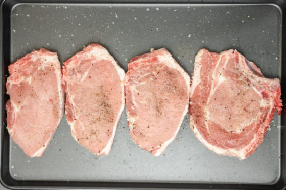seasoned pork chops in a baking tray.