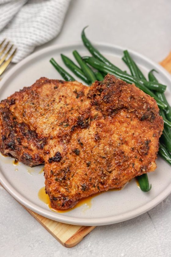 a plate of pork chops and green beans.