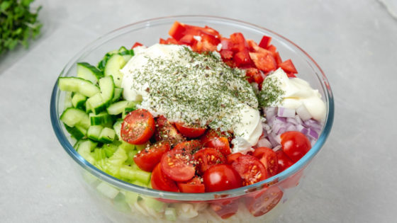 a bowl of freshly chopped vegetable with mayonnaise and herbs.