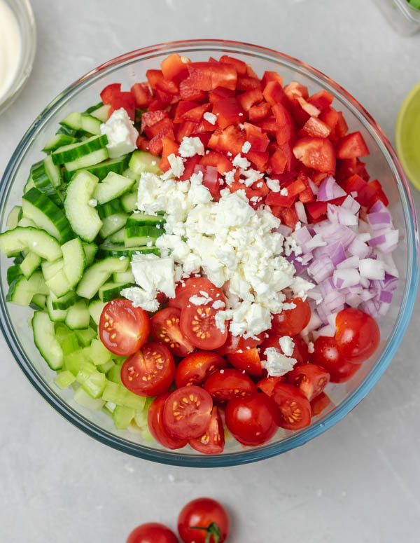 chopped vegetables and crumbled cheese in a bowl.