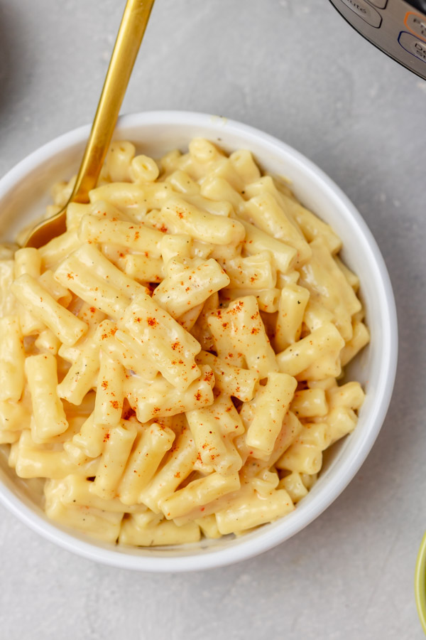 a bowl of mac and cheese place beside an instant pot.
