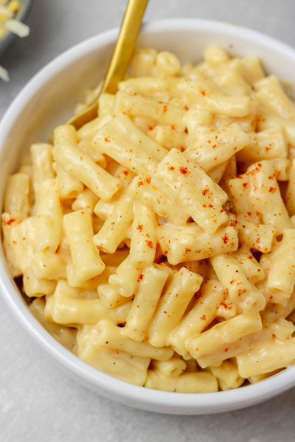 a bowl of mac and cheese garnished with paprika.
