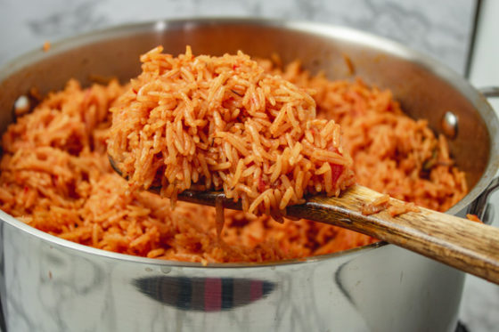 cooked rice on a ladle over a pot.
