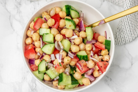 a bowl of chickpea salad with golden serving spoon.