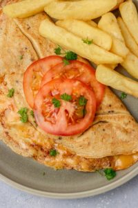 a plate of omelette, tomatoes and chips