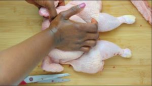hand pressing down on chicken breat.