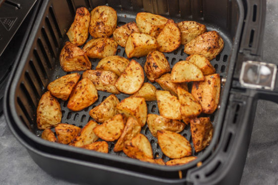 crispy diced potatoes in an air fryer basket.