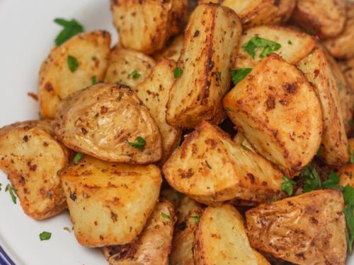 cubed roasted potatoes in an enamel white plate.