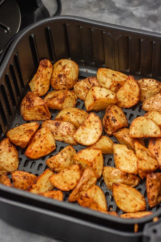 cubed roasted potatoes in air fryer basket.