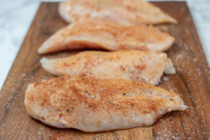 seasoned chicken breasts on a chopping board.