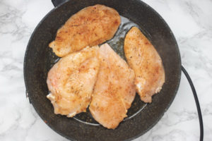chicken breasts searing on a skillet.
