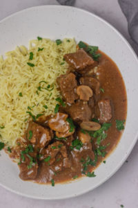 a plate of rice and beef with gravy.