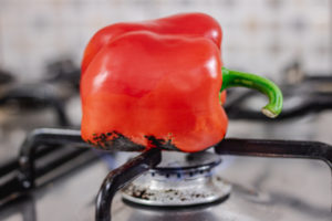 one red bell pepper over a gas burner.