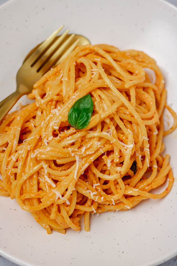 a bowl of spaghetti garnished with grated cheese and basil.