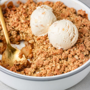 a bowl of apple crumble with two scoops of ice cream.