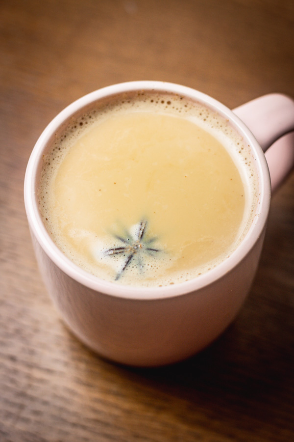 a cup of hot drink with a garnished with star anise.