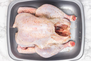 seasoned turkey in a roasting pan.