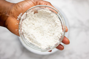 a hand holding a bowl of flour mix.