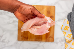 a hand holding chicken breast.
