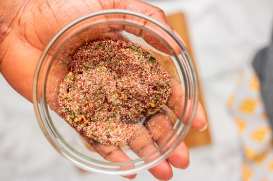 a hand holding a bowl of dry seasoning.