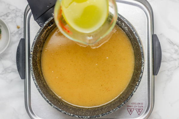 hand pouring liquid in a saucepan.