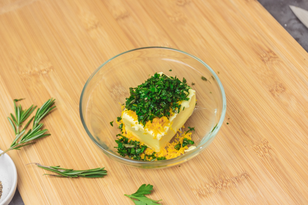 chopped herbs on a block of butter.