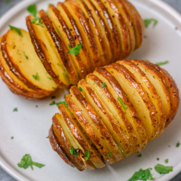 two hasselback potatoes on a side plate.