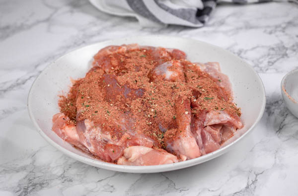 raw chicken and seasoning on a plate.