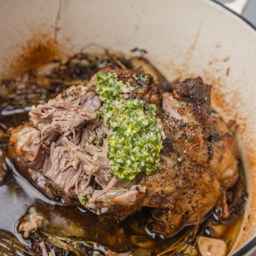 a pot of roast with green sauce spread on it.